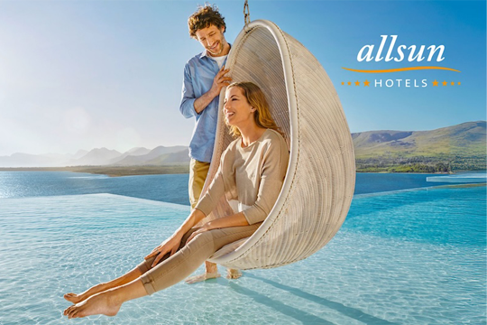 Frau in Muschel Schaukel &uuml;ber einem Pool, Mann steht dahinter mit F&uuml;&szlig;en im Wasser